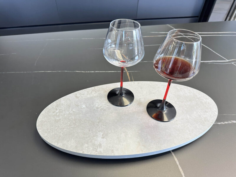 Two wine glasses, one empty, on a modern kitchen countertop.