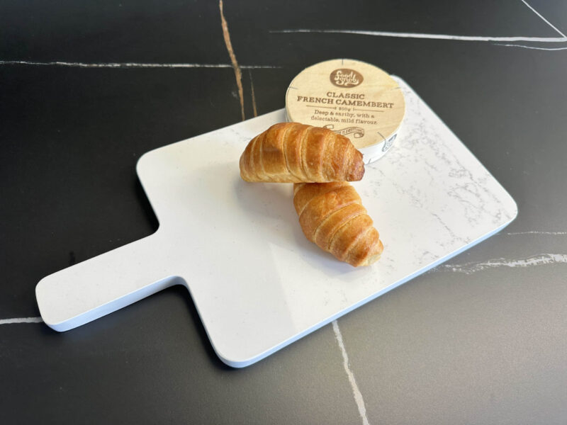 Two croissants and camembert on a marble cutting board.