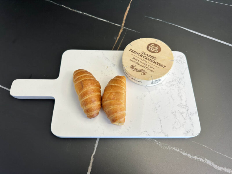 Two croissants and camembert on a marble cutting board.