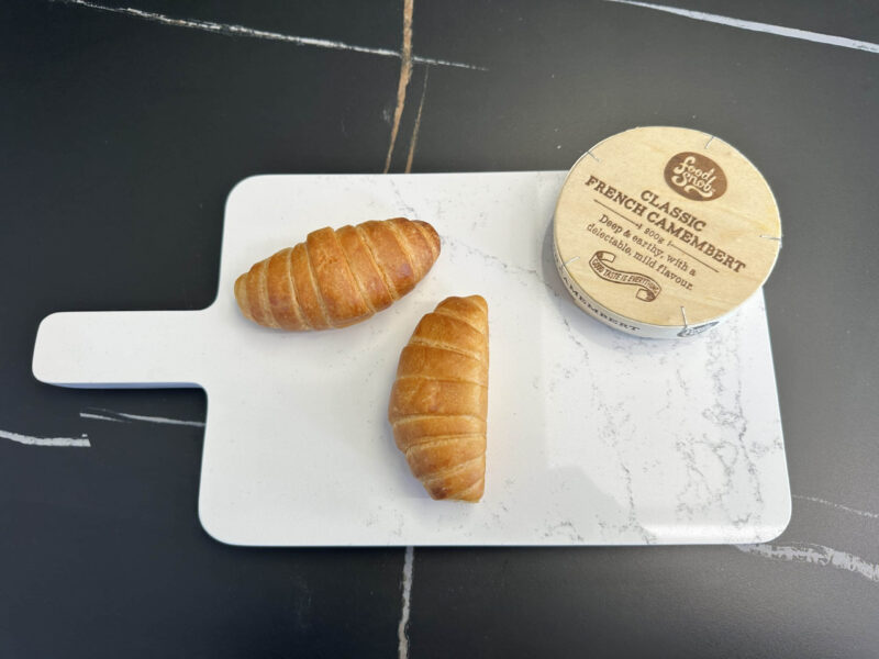 Two croissants and camembert on a white cutting board.
