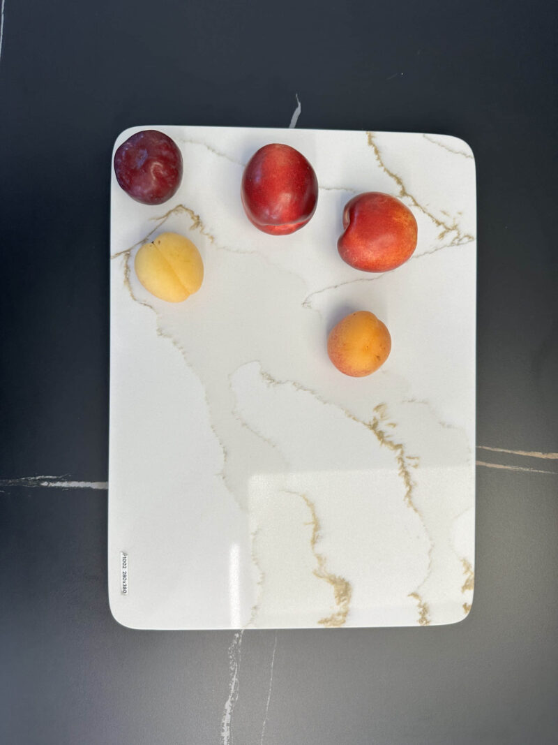 Five fruits on a marble cutting board.