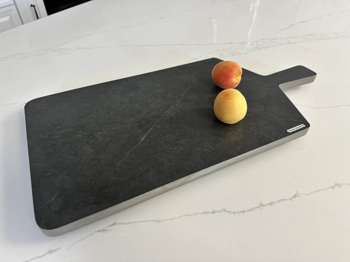 Cutting board with two peaches on a marble countertop.