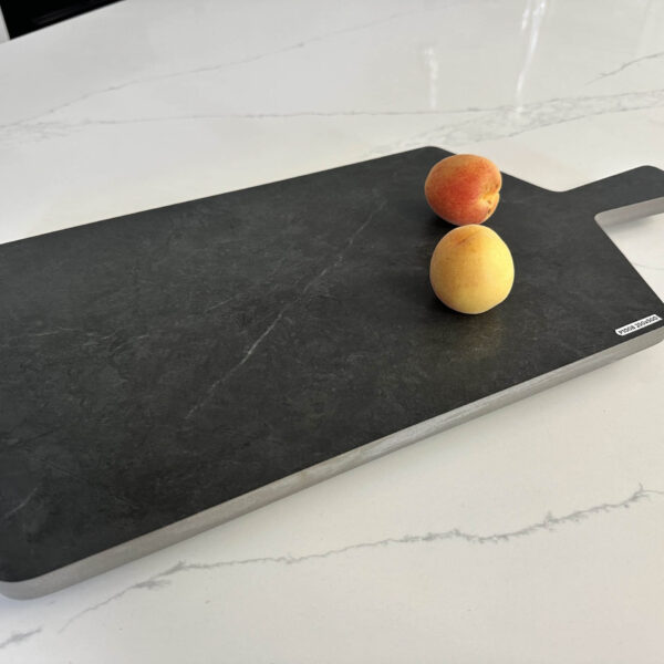 Cutting board with two peaches on a marble countertop.