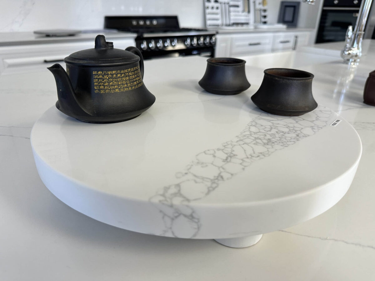Black teapot and cups on a white marble kitchen counter.