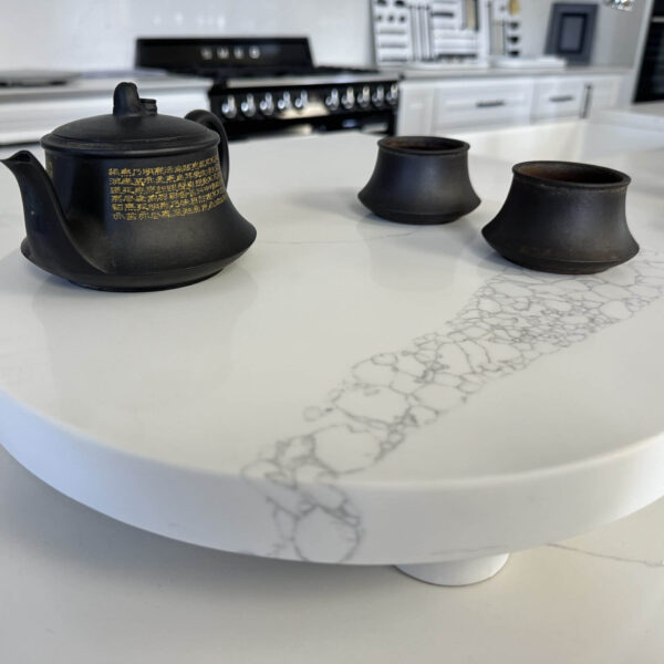 Black teapot and cups on a white marble kitchen counter.