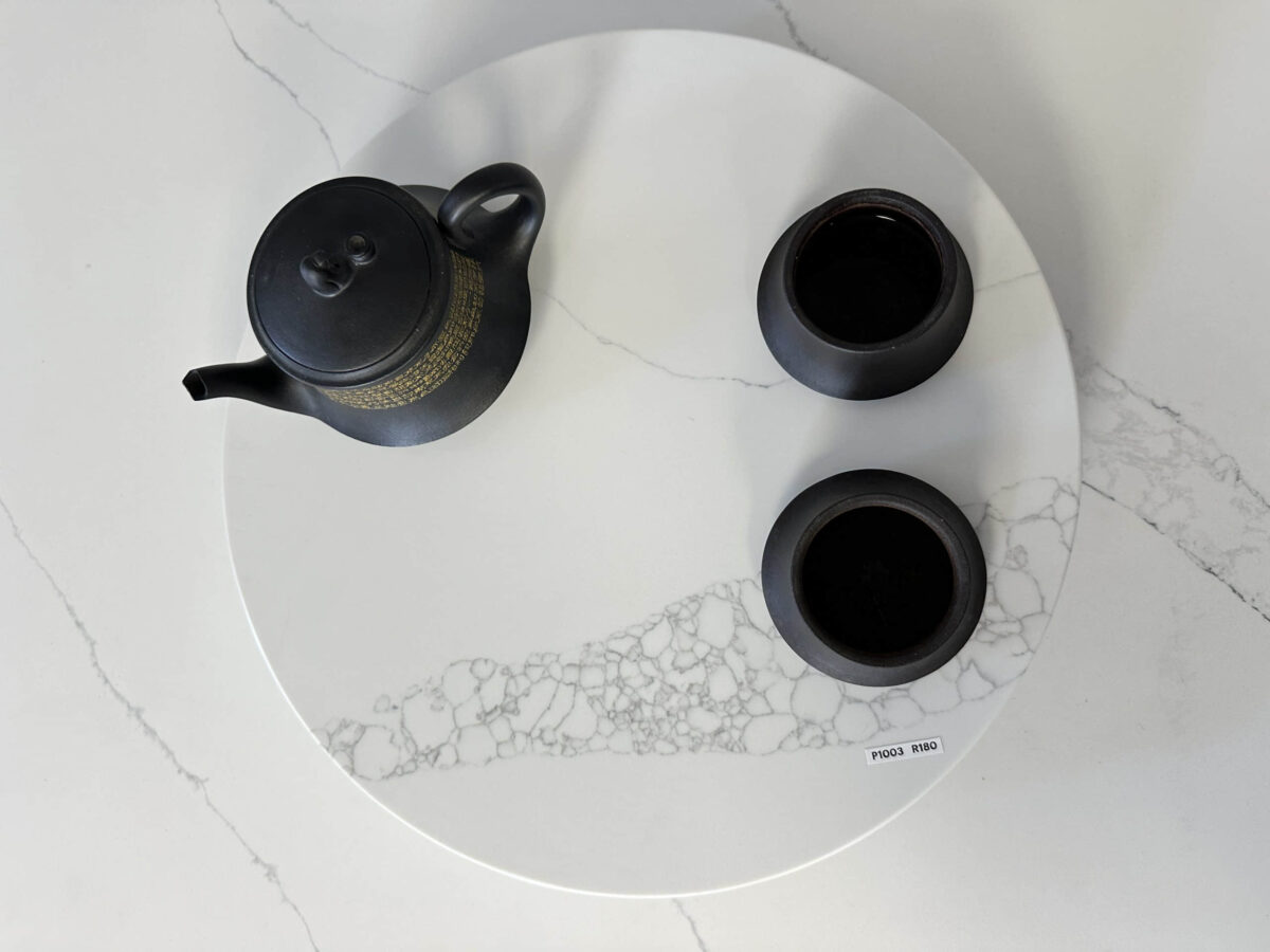 Black teapot and cups on a white marble tray.