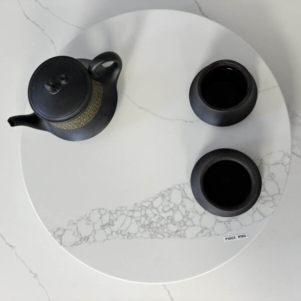 Black teapot and cups on a white marble tray.