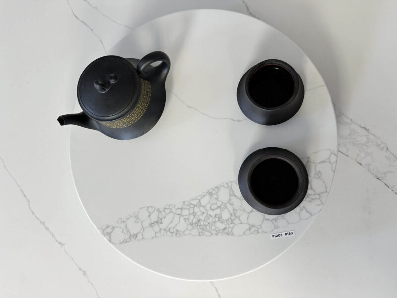 Black teapot and cups on a white marble tray.