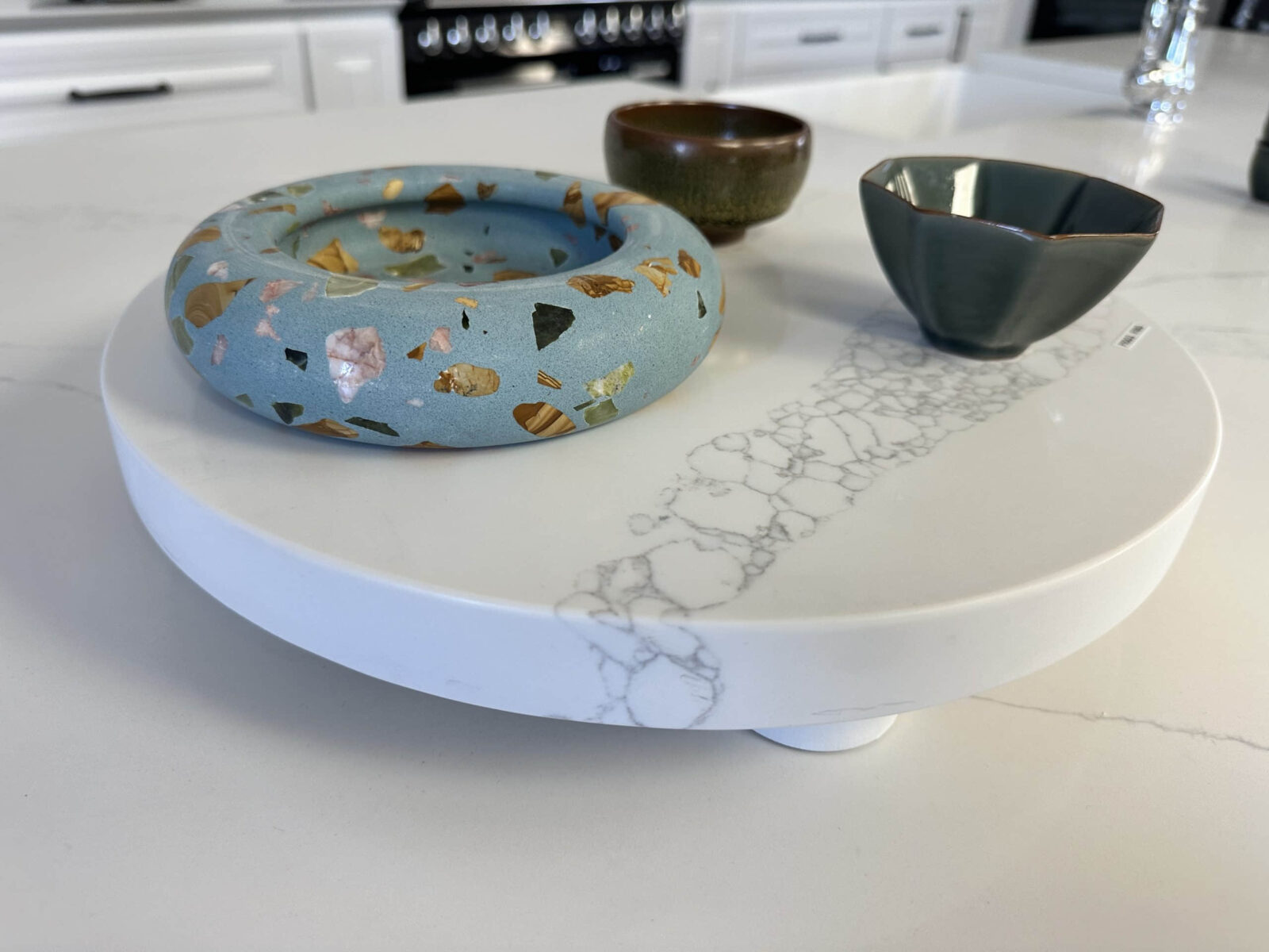 Ceramic bowls on a white marble-patterned serving tray in a kitchen.