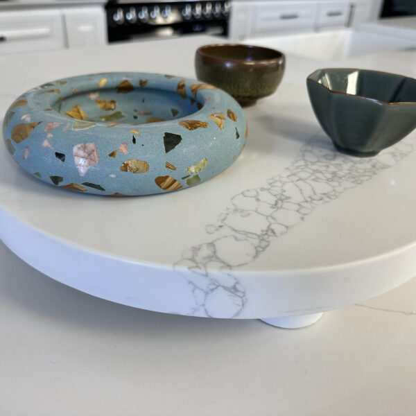 Ceramic bowls on a white marble-patterned serving tray in a kitchen.