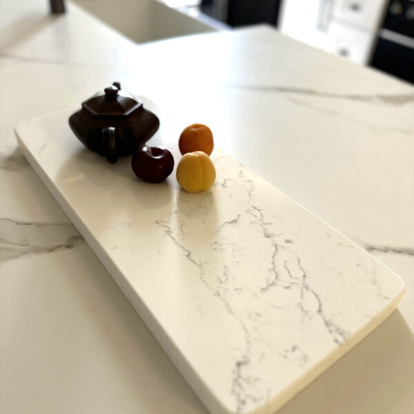 Marble countertop with teapot and three small fruits.