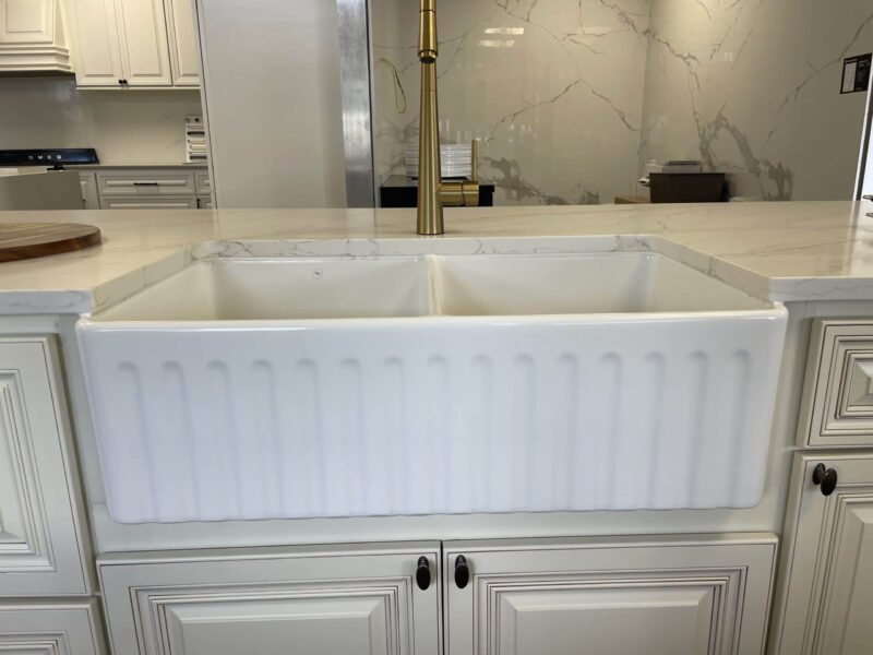 White farmhouse sink with brass faucet in modern kitchen.