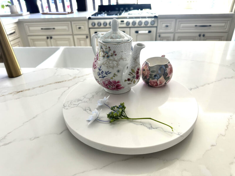 Floral teapot and creamer on marble kitchen counter.