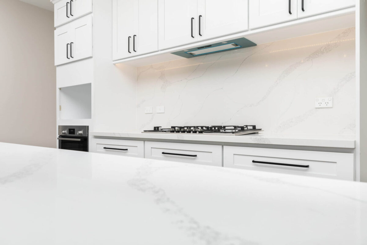 Modern kitchen with white marble countertops and cabinets.