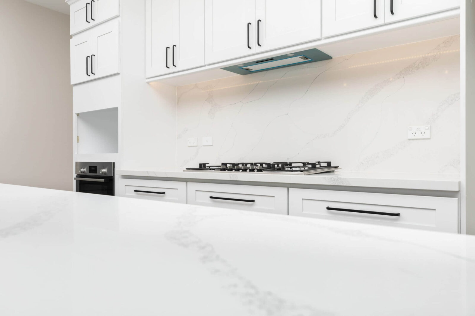 Modern kitchen with white marble countertops and cabinets.