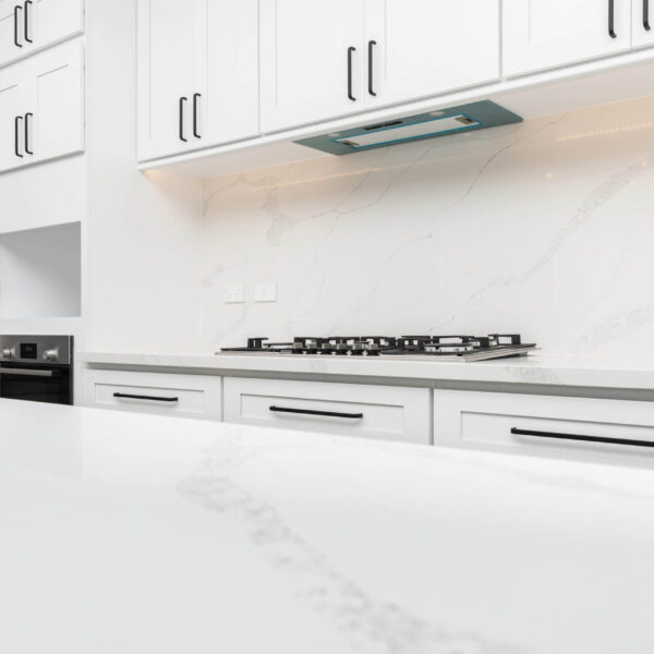 Modern kitchen with white marble countertops and cabinets.