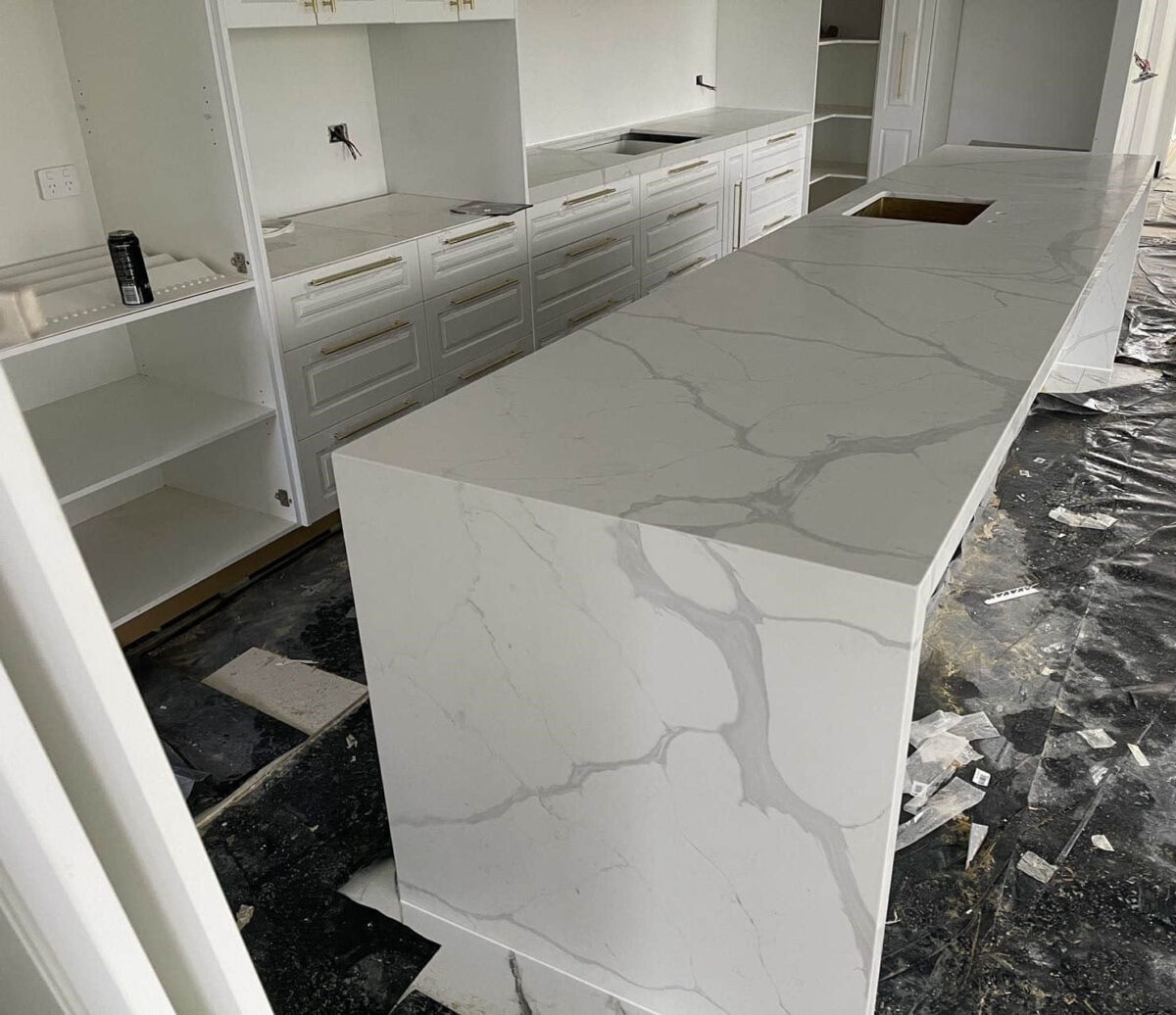 Modern kitchen with marble island countertop under construction.