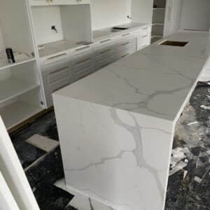 Modern kitchen with marble island countertop under construction.