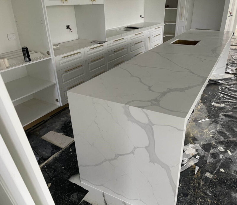 Modern kitchen with marble island countertop under construction.