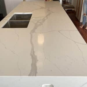 Marble kitchen countertop with sink, person standing nearby.