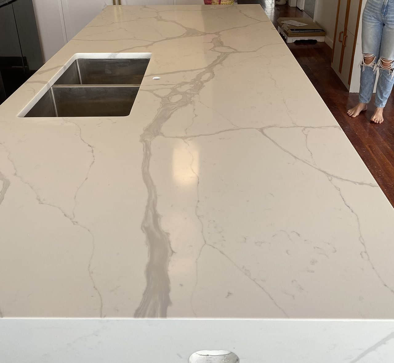 Marble kitchen countertop with sink, person standing nearby.