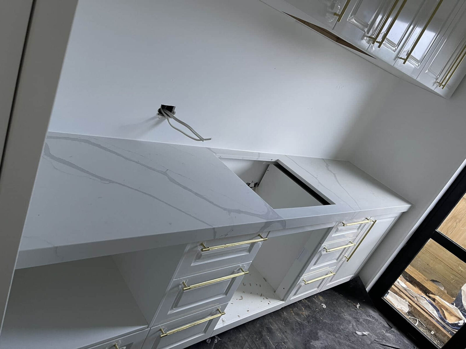 Modern kitchen installation with white cabinets and marble countertops.