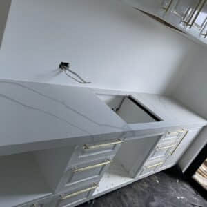 Modern kitchen installation with white cabinets and marble countertops.