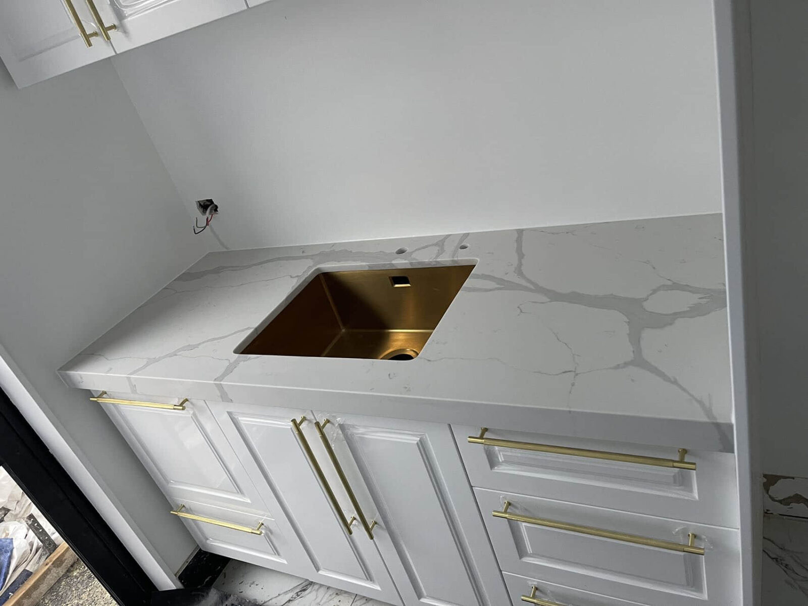 White kitchen countertop with gold sink and handles.