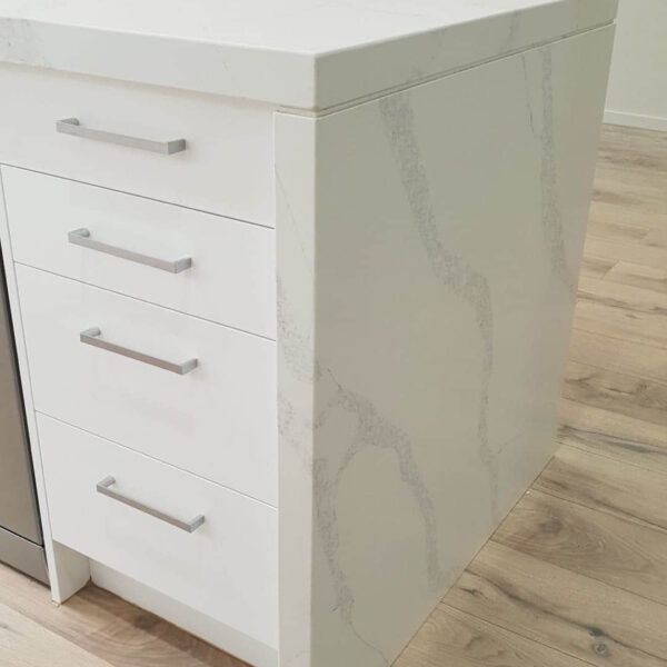 White marble kitchen island with drawers and silver handles.