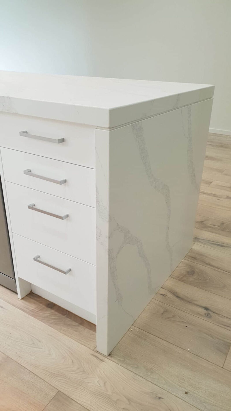 White marble kitchen island with drawers and silver handles.