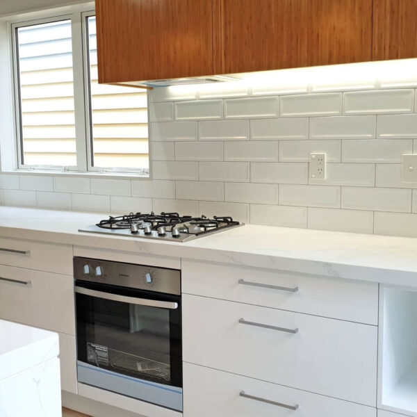 Modern kitchen with white cabinets, marble countertop, and gas stove.