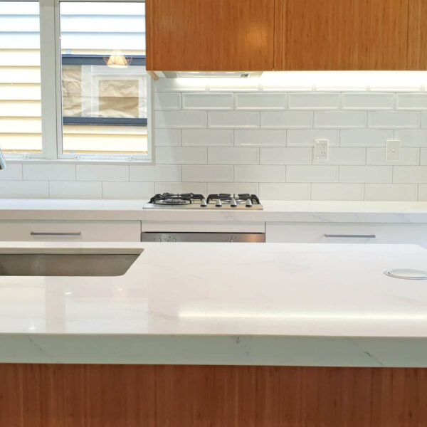 Modern kitchen with white marble countertop and wooden cabinets.