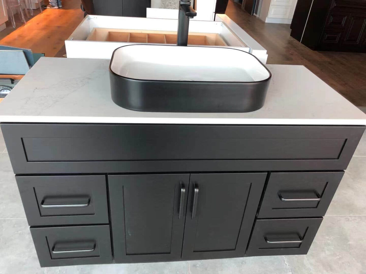 Black bathroom vanity with white countertop and rectangular sink.