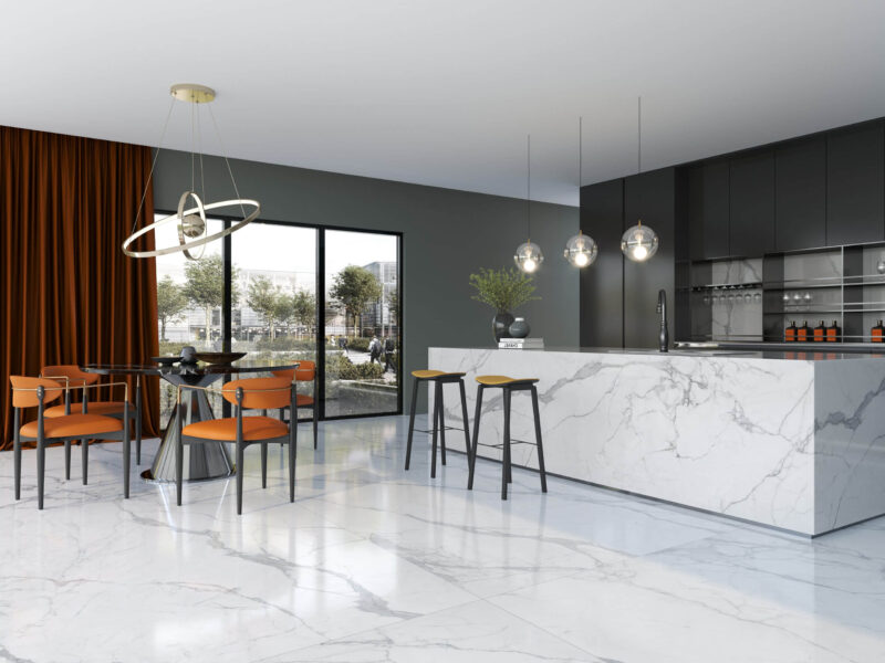 Modern kitchen with marble island, pendant lights, and orange chairs.