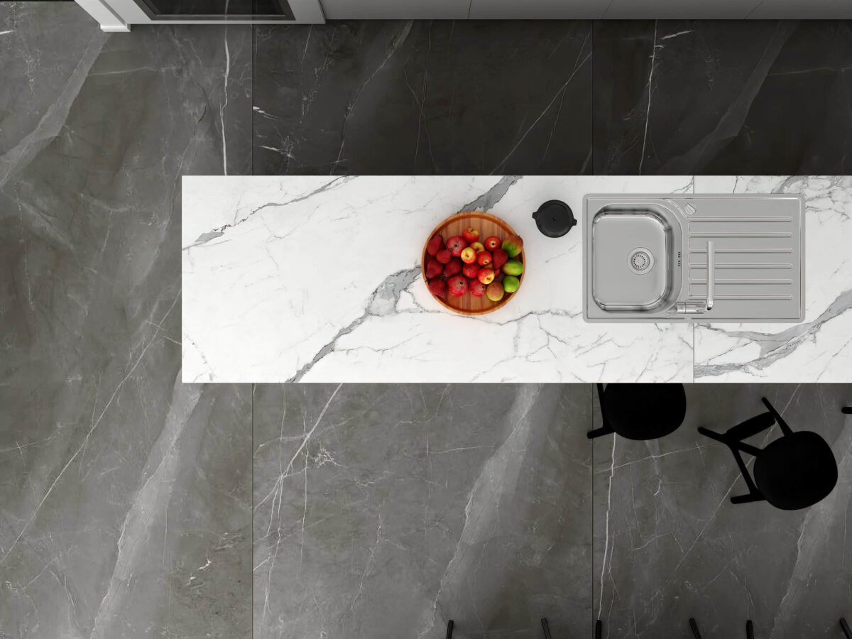 Marble kitchen countertop with fruit bowl and sink, viewed from above.