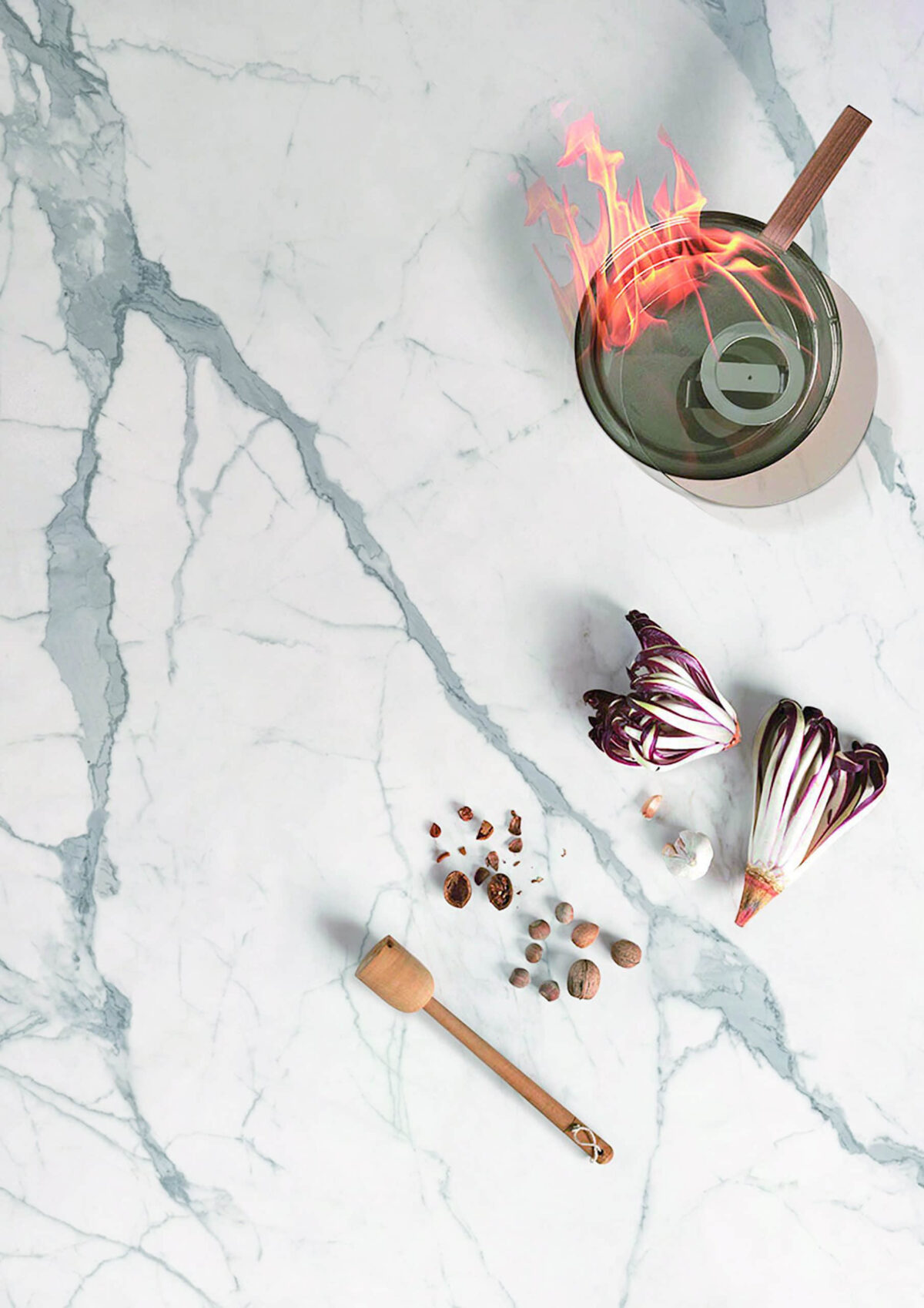 Marble countertop with vegetables, spices, and a flaming pot.