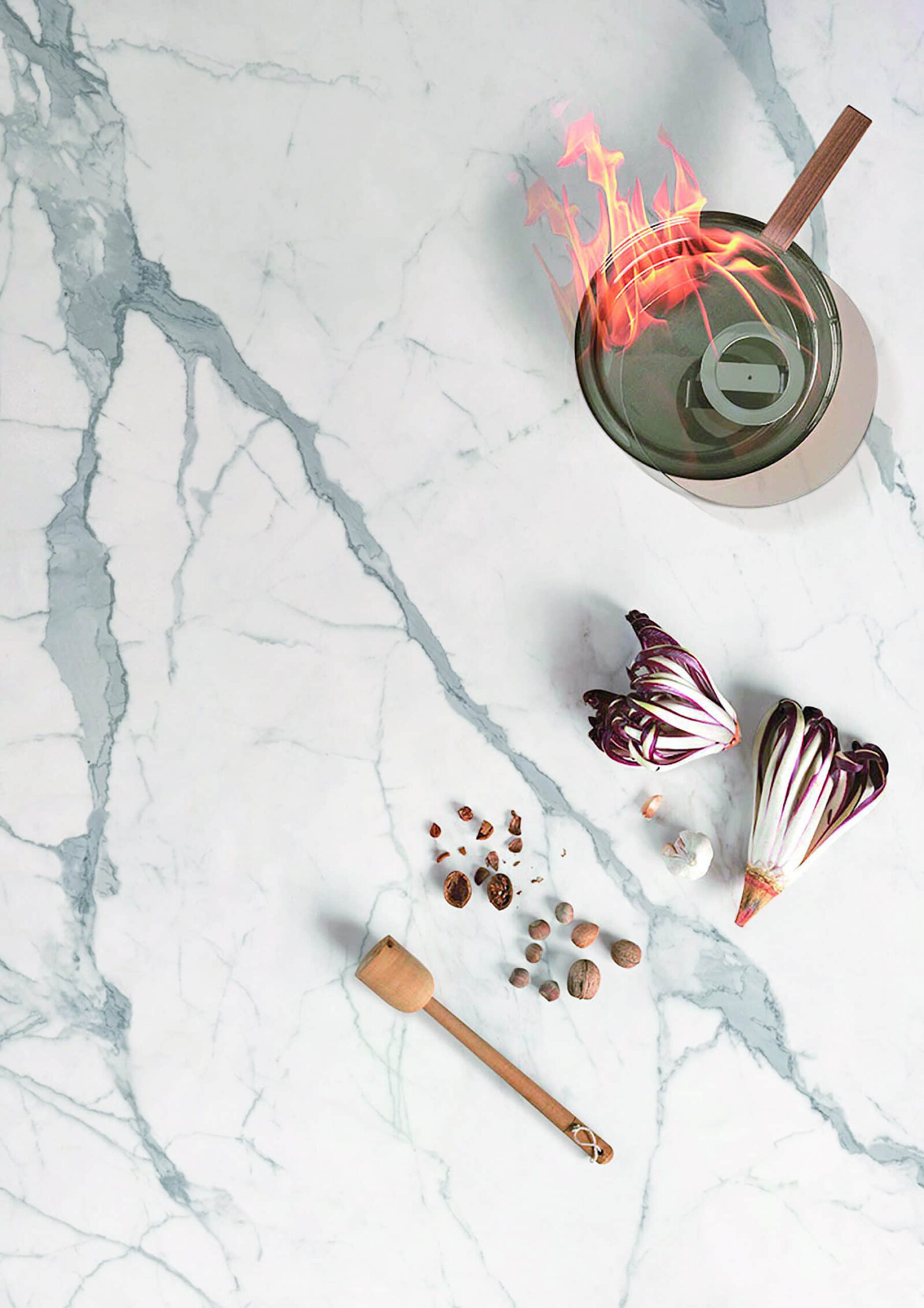 Marble countertop with vegetables, spices, and a flaming pot.