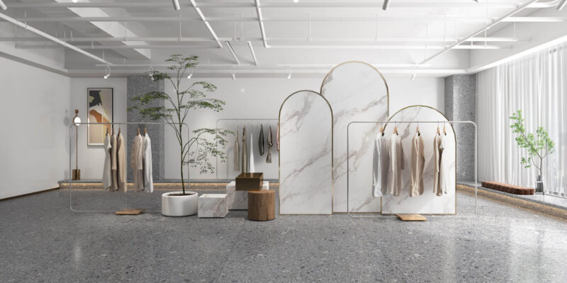 Minimalist clothing store interior with marble dividers and hanging garments.